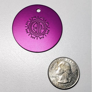 May include: A round, purple metal tag with a hole at the top. The tag has a circular design with the letters "SIP" inside.