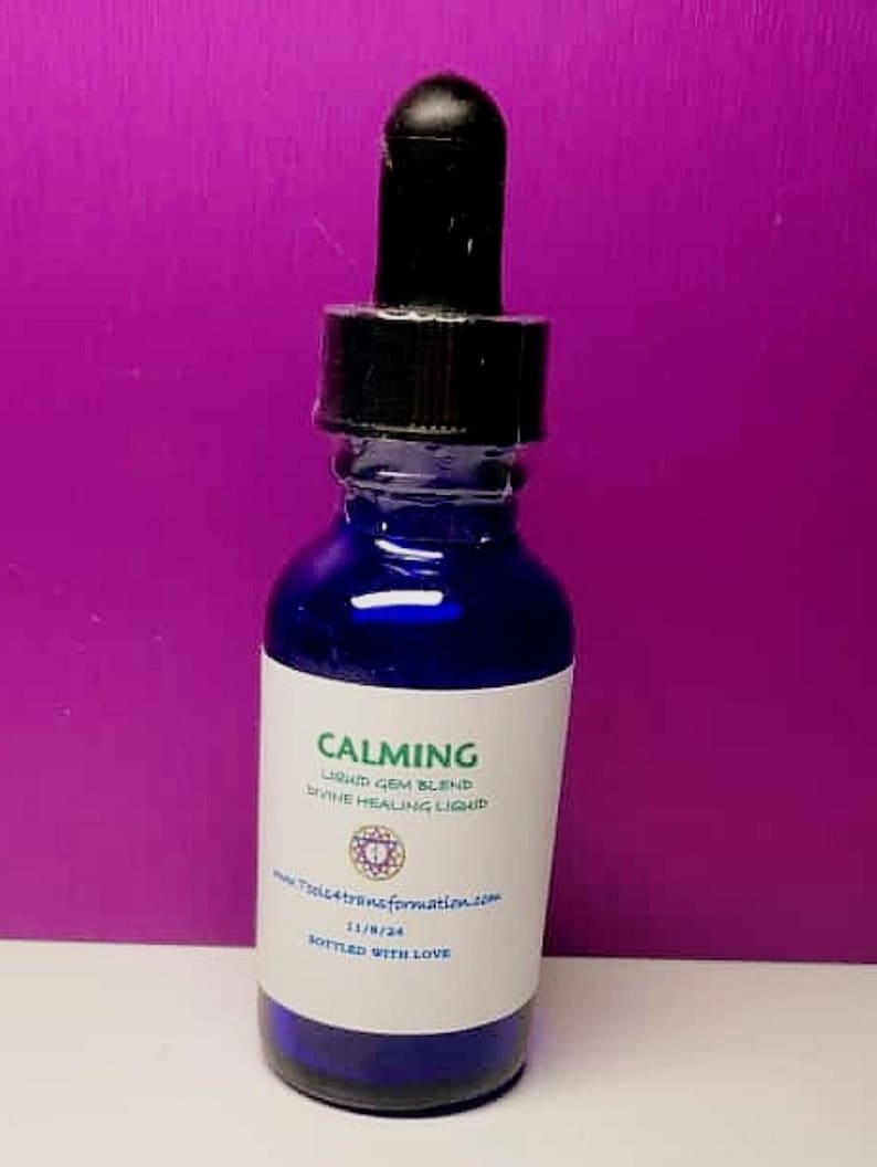 May include: A cobalt blue glass bottle with a black dropper. The label reads "CALMING" and "LIQUID GEM BLEND DIVINE HEALING LIQUID". The bottle contains a clear liquid. The label also includes a website address and the words "BOTTLED WITH LOVE".