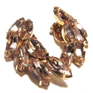 May include: A pair of gold tone clip-on earrings with a cluster of marquise-shaped, clear, faceted rhinestones.