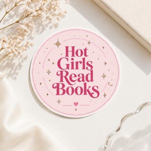 Könnte beinhalten: Ein runder Aufkleber mit dem Text "Hot Girls Read Books" in rosa Schrift. Der Aufkleber hat einen hellrosa Hintergrund mit goldenen Sternen und einem Herzdesign. Der Aufkleber liegt auf einer weißen Oberfläche.