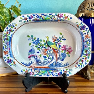 May include: A white porcelain serving dish with a blue and gold rim. The dish features a colorful floral design with two birds, one green and one blue, perched on a branch.