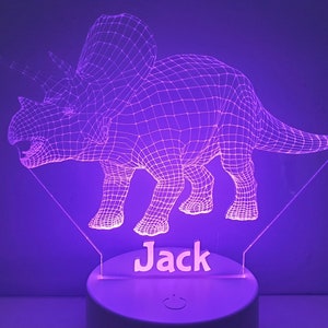 K&ouml;nnte beinhalten: Ein lilafarbenes 3D-gedrucktes Nachtlicht in Form eines Triceratops-Dinosauriers mit dem Namen "Jack" darunter.