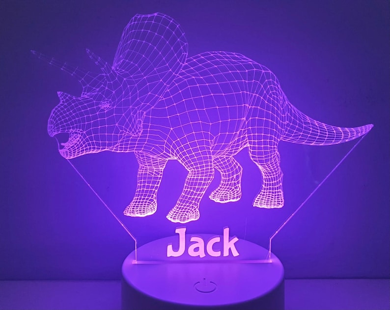 K&ouml;nnte beinhalten: Ein lilafarbenes 3D-gedrucktes Nachtlicht in Form eines Triceratops-Dinosauriers mit dem Namen "Jack" darunter.