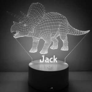 K&ouml;nnte beinhalten: Ein wei&szlig;es, 3D-gedrucktes Dinosaurier-Nachtlicht mit dem Namen "Jack" darunter. Der Dinosaurier ist ein Triceratops mit einem Drahtgitterdesign.