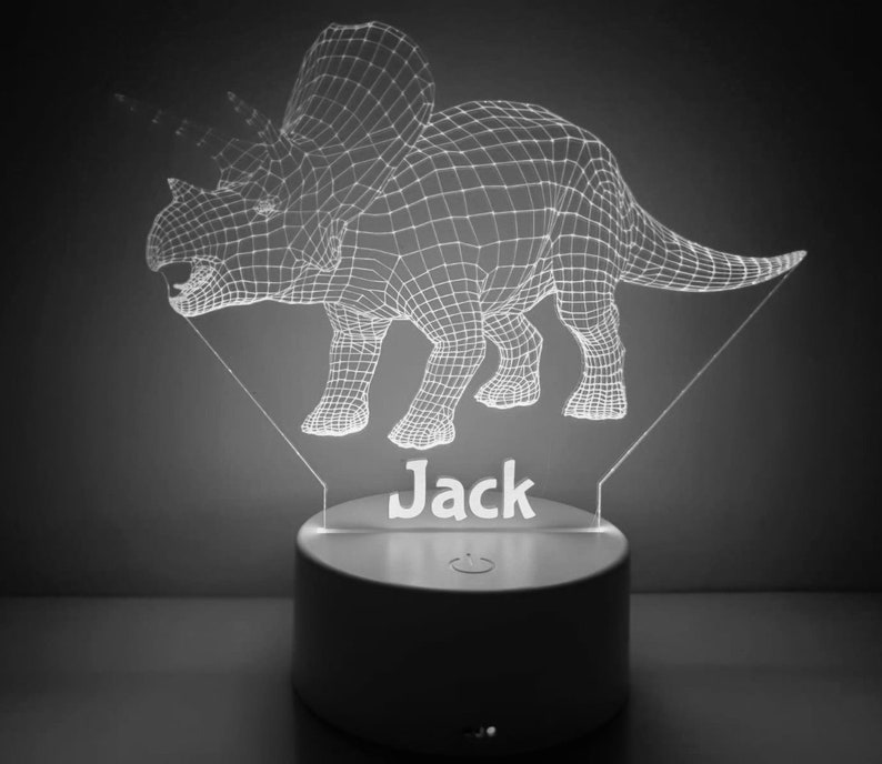 K&ouml;nnte beinhalten: Ein wei&szlig;es, 3D-gedrucktes Dinosaurier-Nachtlicht mit dem Namen "Jack" darunter. Der Dinosaurier ist ein Triceratops mit einem Drahtgitterdesign.