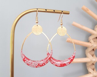 May include: Gold hoop earrings with a red and white floral design. The earrings have a round gold disc at the top.