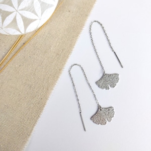 Peut inclure: Une paire de boucles d'oreilles en argent en forme de feuille de ginkgo avec une chaîne délicate. Les boucles d'oreilles sont pendantes et ont une finition texturée.