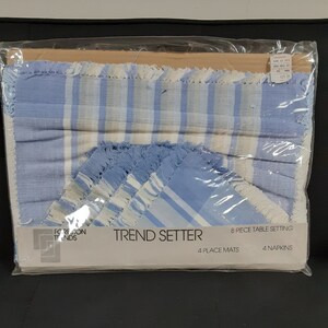 May include: A set of blue and white striped placemats and napkins with a fringed edge. The set is packaged in a clear plastic bag and includes the text "TREND SETTER", "8 PIECE TABLE SETTING", "4 PLACE MATS", and "4 NAPKINS".
