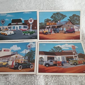 May include: Four vintage postcards depicting scenes of roadside businesses from the 1950s. Each postcard features a different business, including a diner, a gas station, an auto camp, and a tourist supply store. The postcards are all in color and feature vintage cars and signage.