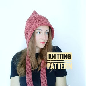 Könnte beinhalten: Ein Strickmuster für eine Kapuze mit einem langen Schal. Die Mütze und der Schal sind in einem staubigen Rosaton.