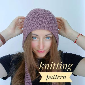 Könnte beinhalten: Ein Strickmuster für eine lila Mütze mit einem langen Schal. Das Muster ist in englischer Sprache geschrieben.
