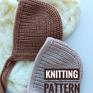 Könnte beinhalten: Zwei gestrickte Baby-Mützen in Braun und Beige mit Bändern. Die Mützen liegen auf einer weißen, flauschigen Oberfläche. Der Text "Knitting Pattern" ist im Bild sichtbar.