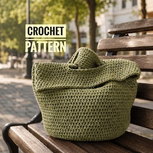 May include: A green crochet bag with a folded-over top sits on a wooden bench. The bag is made of a textured, olive-green yarn. The words "CROCHET PATTERN" are in a white box in the upper left corner.