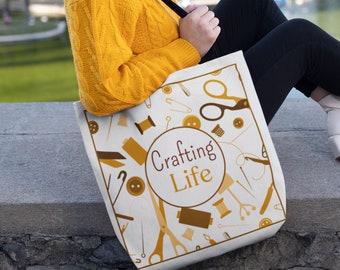 May include: A white tote bag with a brown and yellow pattern of sewing and crafting supplies. The bag has the text "Crafting Life" in a circle.