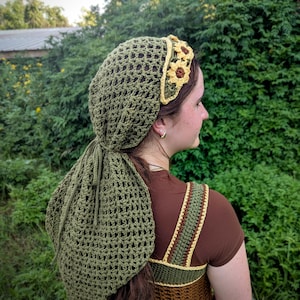 Könnte beinhalten: Olivgrüne Häkelkopfbedeckung und passender Kordelzugbeutel. Die Kopfbedeckung hat ein Blumenstirnband mit gelben und braunen Blumen. Das Häkeltop ist braun mit grünen und gelben Trägern.