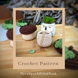 May include: Crochet pattern for an acorn-shaped container with a brown top and a beige bottom. The container is open and a gold chain necklace is inside. The text "OnceUponAStitchNook" is at the bottom of the image.