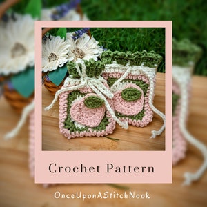 May include: Crochet pattern for two small peach-shaped bags with green, pink, and white yarn. The bags have a drawstring closure and are perfect for small items. The pattern is called "Once Upon A Stitch Nook".