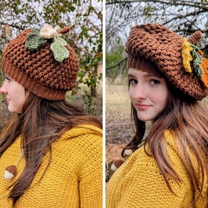 Puede incluir: Un gorro de ganchillo marrón con un diseño de hojas y bellotas. El sombrero es de color marrón cálido y presenta un patrón texturizado. Las hojas son verdes, naranjas y crema. La persona lleva un jersey amarillo.
