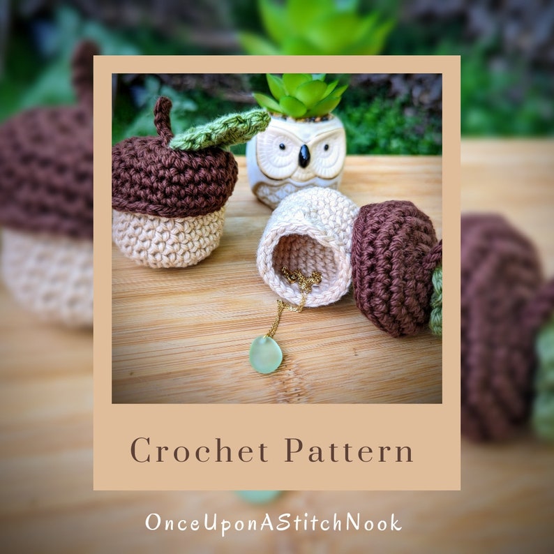 May include: Crochet pattern for acorn shaped containers. The containers are beige and brown with green leaves. The containers are open and show a gold necklace and a green stone pendant inside.