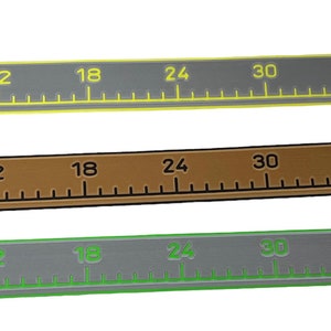 Pu&ograve; includere: Tre righelli piatti e rettangolari, lunghi ciascuno 122 cm. Il righello superiore &egrave; grigio scuro con segni gialli, quello centrale &egrave; marrone con segni neri e quello inferiore &egrave; grigio chiaro con segni verdi. Ognuno presenta una piccola bandiera.