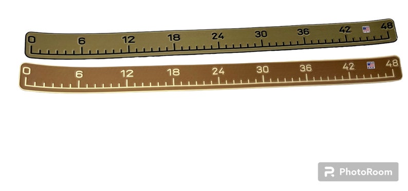 Pu&ograve; includere: Due nastri di misurazione flessibili, uno verde oliva e uno marrone, contrassegnati con incrementi numerici neri o bianchi da 0 a 122 cm. Entrambi i nastri presentano un piccolo logo rettangolare sul lato destro e una forma curva e allungata.