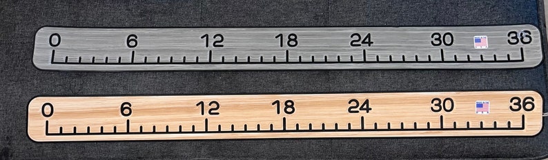 May include: Two rulers, one silver and one wood, both with black markings and numbers from 0 to 36 inches. The rulers have a small American flag graphic at the 30-inch mark.