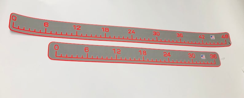 May include: Two flexible rulers with a gray background and red markings. The top ruler is curved and measures up to 48 inches. The bottom ruler is straight and measures up to 36 inches.