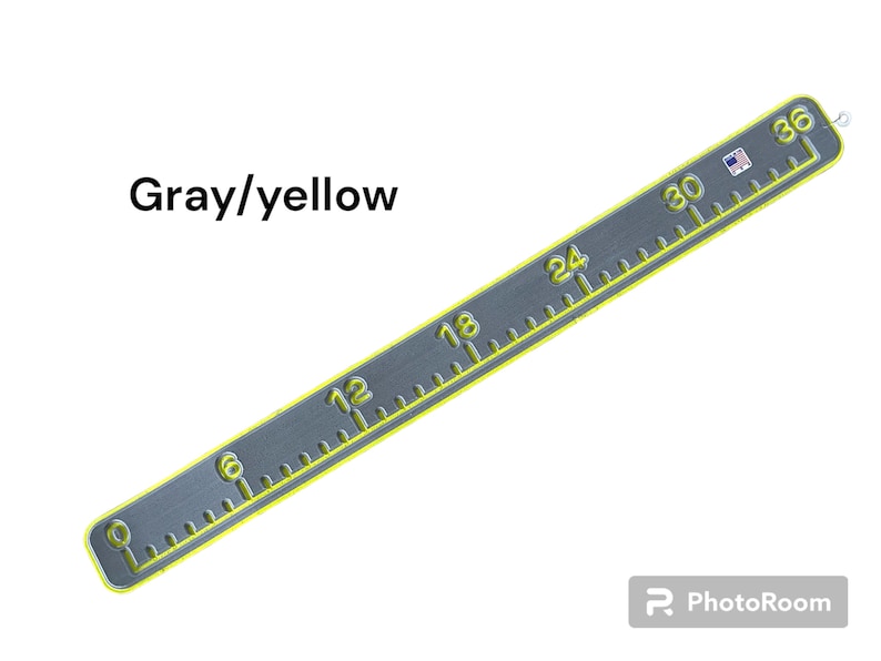 May include: Gray and yellow measuring tape with markings in inches from 0 to 36. The tape is made of metal and has a yellow border.