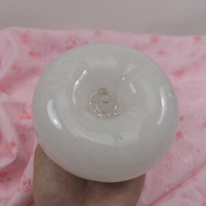 May include: A white glass apple with a clear glass stem and a smooth, shiny surface.
