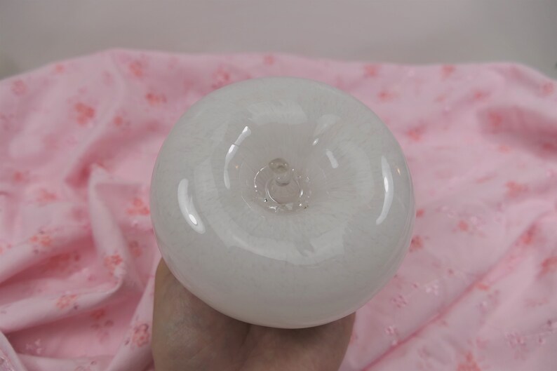 May include: A white glass apple with a clear glass stem and a smooth, shiny surface.