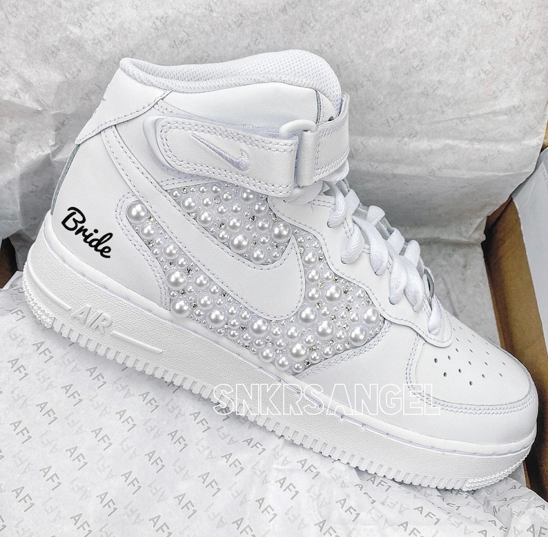 K&ouml;nnte beinhalten: Wei&szlig;e High-Top-Sneaker mit Perlenbesatz und dem Wort "Bride" auf der Seite bestickt.