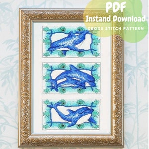 May include: A framed cross stitch pattern featuring three blue dolphins swimming in a turquoise and green seascape. The pattern is titled "Instant Download Cross Stitch Pattern" and is available as a PDF.