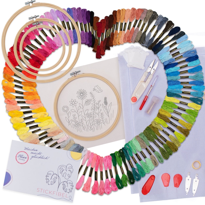 May include: A colourful embroidery kit with a variety of embroidery floss, hoops, needles, and a printed pattern. The kit includes a variety of colours, including pink, blue, green, yellow, and orange. The kit also includes a small card with the text "Machen macht gl&uuml;cklich!" and "Blissetivity" and "STICKFIBEL".