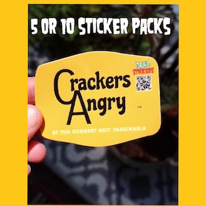 May include: A yellow rectangular sticker with rounded corners featuring the black text Crackers Angry and the phrase AT THE DUMBEST SHIT IMAGINABLE. The sticker includes a small QR code and the text DANG STICKERS. Text above reads 5 OR 10 STICKER PACKS.