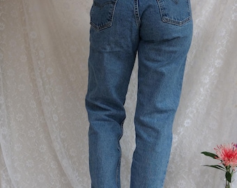 May include: A pair of blue denim jeans with a high waist and a straight leg. The jeans have a brown leather patch on the back with the Levi's logo and the text "Levi's Original 501® Jeans".