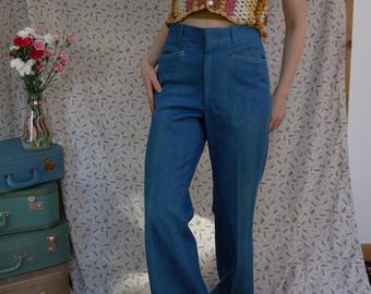 May include: A woman wearing a striped crochet top and high-waisted blue denim bell bottom trousers.