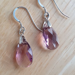May include: A pair of silver dangle earrings with teardrop-shaped amethyst crystals.