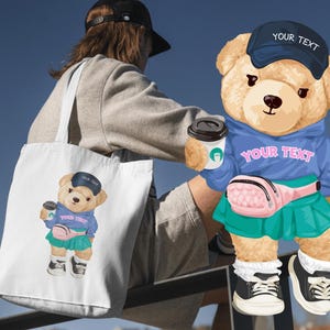 May include: A white tote bag featuring a cartoon teddy bear wearing a blue hoodie, a pink fanny pack, and a green skirt. The bear is holding a coffee cup and wearing a blue cap with the text "YOUR TEXT". The bear is also featured on a blue hoodie.