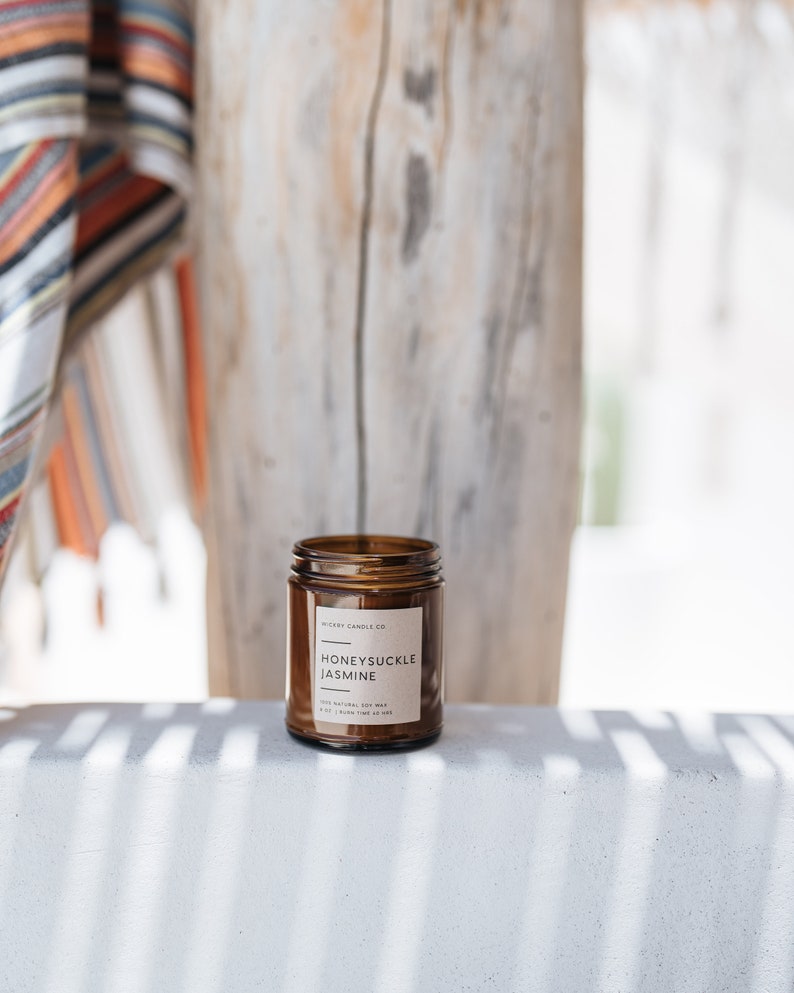 May include: A brown glass candle jar with a white label that reads "Honeysuckle Jasmine" and "Wicary Candle Co.".