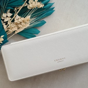 May include: White rectangular jewelry box with a stitched edge and the text "CHAMAC LONDON" embossed on the top.