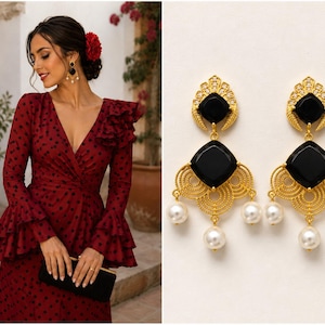 May include: A woman in a red polka dot dress with long sleeves and ruffled detailing, holding a black clutch. The image also features gold earrings with black square stones and dangling pearls.