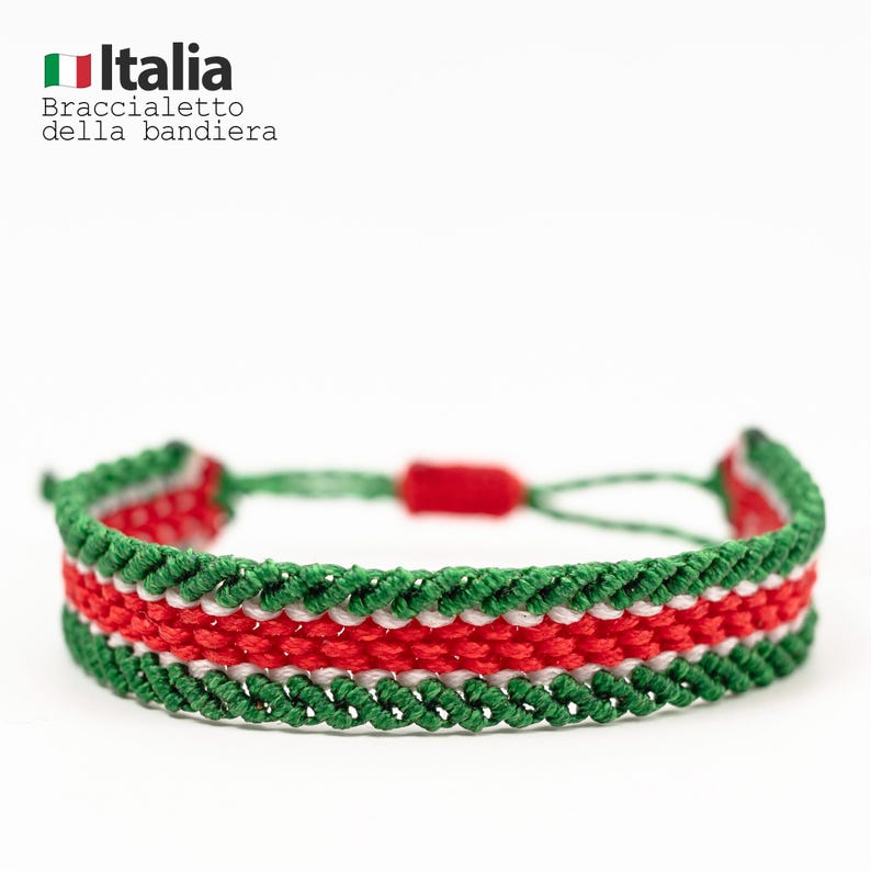 Puede incluir: Una pulsera tejida con los colores de la bandera italiana: verde, blanco y rojo. La pulsera est&aacute; hecha de hilos trenzados y tiene un cierre ajustable. El texto "Italia Braccialetto della bandiera" es visible en la esquina superior izquierda.