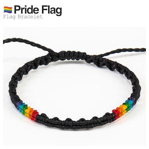 Könnte beinhalten: Schwarzes Makramee-Armband mit regenbogenfarbenen Perlen. Das Armband trägt den Text "Pride Flag" und "Flag Bracelet". Die Regenbogenperlen repräsentieren die Farben der Pride-Flagge.