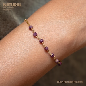 Puede incluir: Una delicada pulsera de cadena dorada adornada con piedras preciosas de rubí facetadas. La pulsera se muestra en una muñeca. La imagen incluye el texto "NATURAL Gemstones Bracelet" y "Ruby Rondelle Faceted".