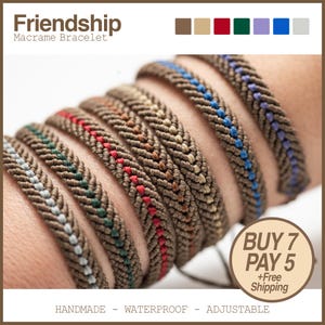 Puede incluir: Una colección de pulseras de amistad de macramé hechas a mano en varios colores, incluyendo verde, rojo, azul y morado. Las pulseras son marrones con costuras coloridas. La palabra "Friendship" está en la parte superior de la imagen. Las pulseras son impermeables y ajustables.
