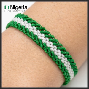 Könnte beinhalten: Ein grün-weißes Makramee-Armband in den Farben der nigerianischen Flagge. Das Armband wird am Handgelenk getragen. Der Text "Nigeria Flag Bracelet" befindet sich in der oberen linken Ecke.