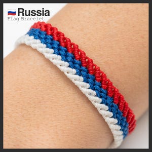 May include: A red, white and blue braided bracelet with the text "Russia Flag Bracelet".