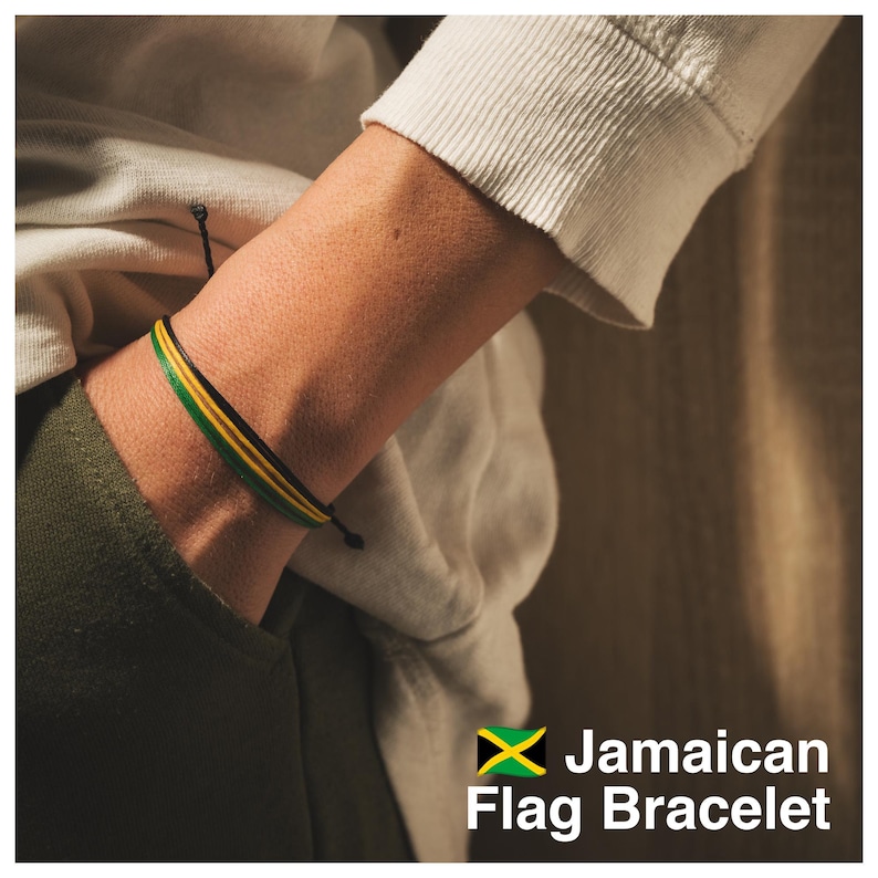 K&ouml;nnte beinhalten: Armband mit den Farben der jamaikanischen Flagge: Gr&uuml;n, Gelb und Schwarz. Das Armband wird am Handgelenk getragen. Der Text lautet "Jamaican Flag Bracelet" mit der jamaikanischen Flagge unten rechts.