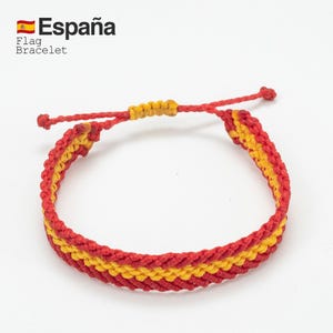 May include: Red and yellow woven bracelet, featuring the colors of the Spanish flag. The bracelet has a sliding knot closure for adjustable sizing. Text on the image reads "Espa&ntilde;a" and "Flag Bracelet".