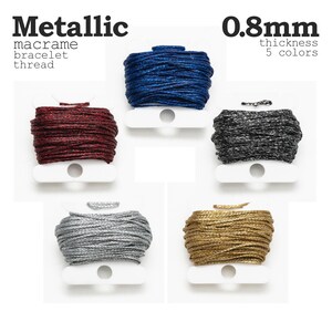 May include: Five spools of metallic macrame bracelet thread in various colors: blue, burgundy, black, silver, and gold. The thread is 0.8mm thick. The word "Metallic" and "macrame bracelet thread" are printed at the top.